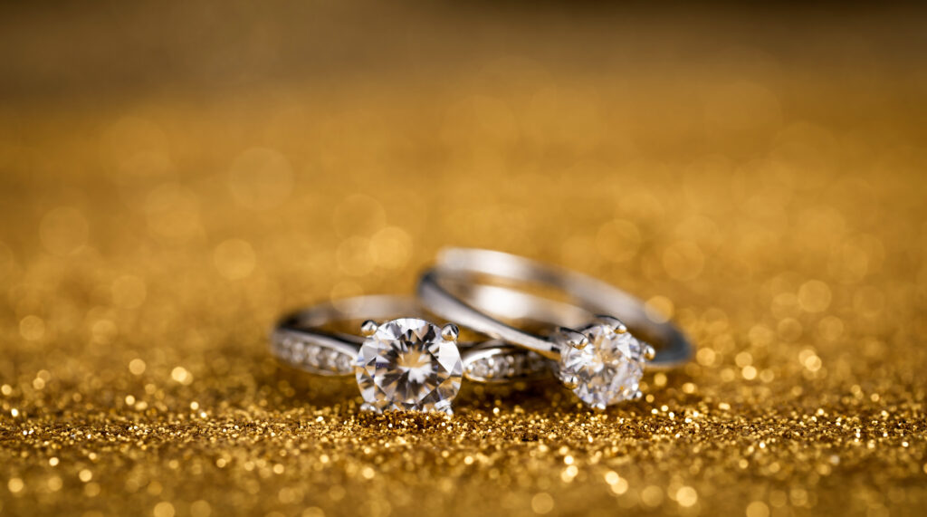 Closeup shot of two diamond rings on a golden surface